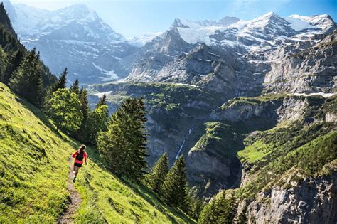 Woman trail running on singletrack above Lauterbrunnen Valley with views of the Jungfrau and ...