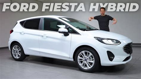 a man standing next to a white car in front of a sign that says ford ...