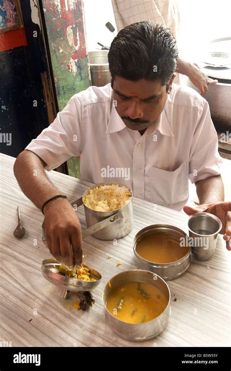 Man eating rice with sambar and vegetable curry from his tiffin box ...