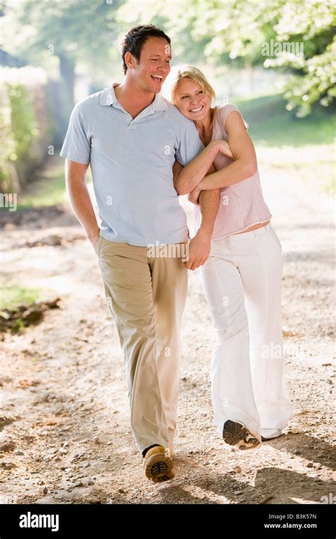 Couple walking outdoors arm in arm smiling Stock Photo - Alamy