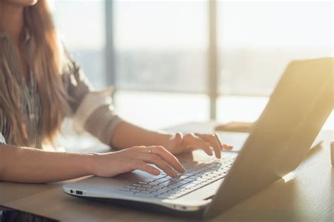 Female writer typing using laptop keyboard at her workplace in the morning. Woman writing blogs ...