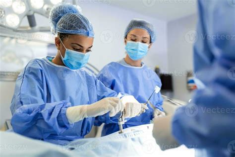 Concentrated female surgeon performing surgery with her team in hospital operating room. Medics ...