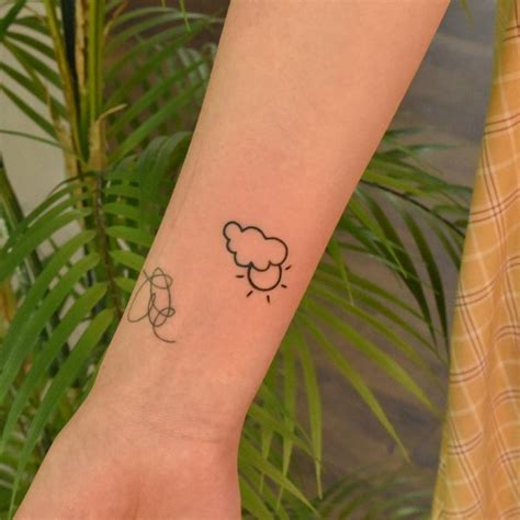 Sun and cloud tattoo done on the wrist, line art style.