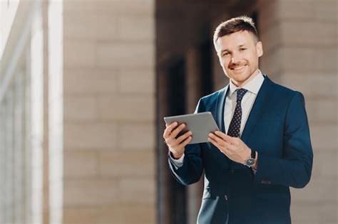 Premium Photo | Smiling professional in a suit using a tablet with a columned building in the ...