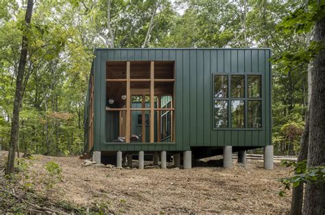 This dark green cabin floats above a sloping terrain in a forest in Connecticut - Yanko Design