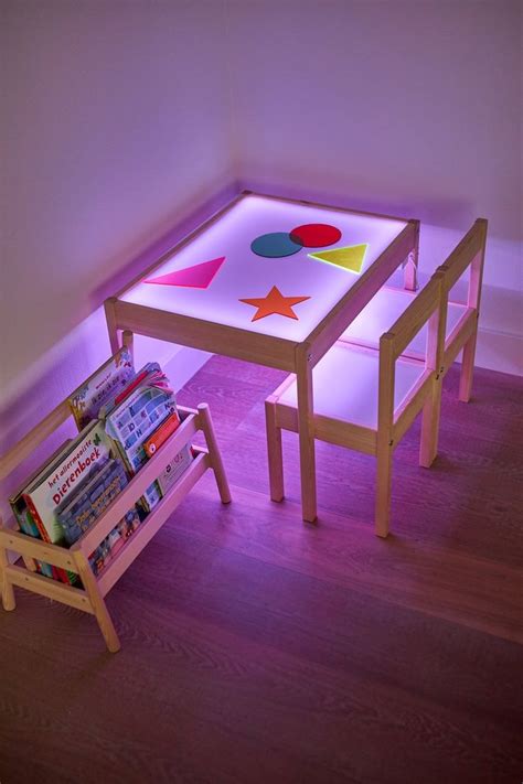 an illuminated table and bench with books on it in a room that has ...