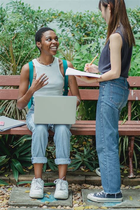 Multiethnic women talking outdoors with computer and notepad · Free Stock Photo