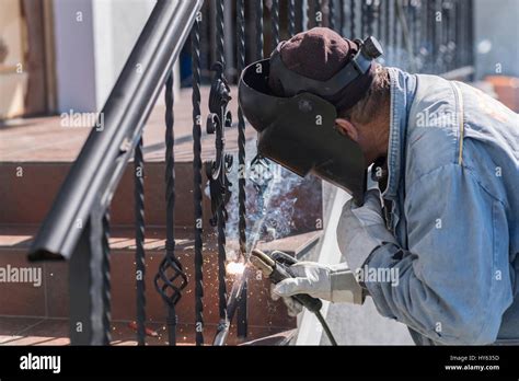 A worker welding metal handrails on the stairs. Wrought iron railings. Private house. Ukraine ...