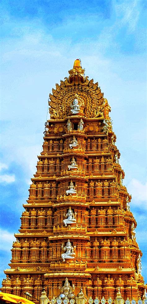 a very tall tower with statues on it's sides in front of a blue sky