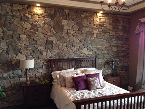 a bedroom with a stone wall behind the bed