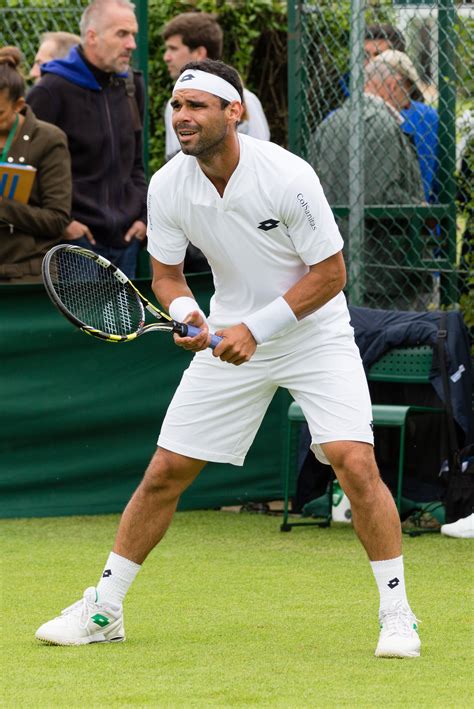 a man holding a tennis racquet on top of a grass covered tennis court