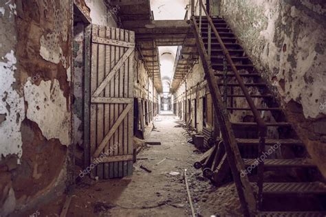 Abandoned prison cell walkway with old rusty stairs, doors and peeling ...