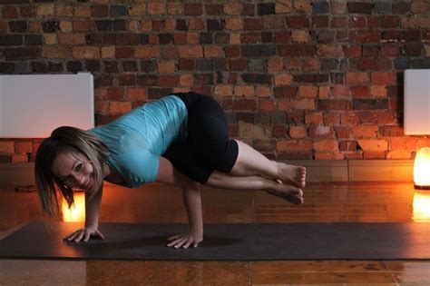 a woman doing a handstand on a yoga mat in front of a brick wall