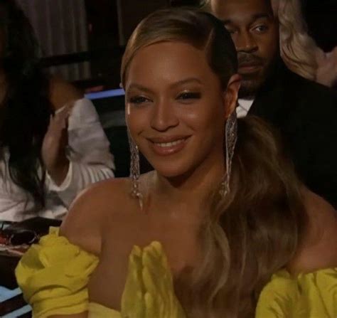 a woman in a yellow dress sitting next to other people at a table and smiling