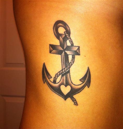 an anchor tattoo on the back of a woman's lower body, with a cross and heart