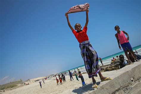 A Somali boy holds a shirt aloft to dry in… | Free public domain photo