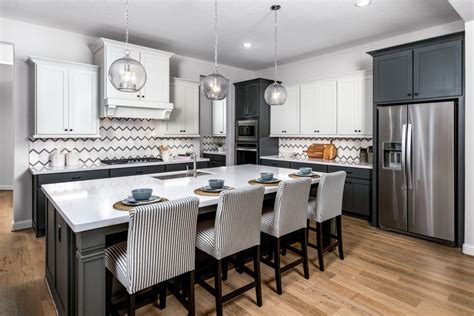 a kitchen with white cabinets and black countertops, an island in the middle is surrounded by ...