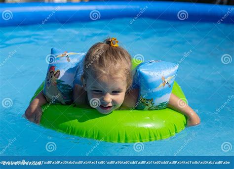 A Cute Little Girl Floats on an Inflatable Ring in the Blue Water of the Pool. in Summer ...