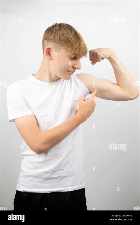 Portrait of a 14 year old caucasian teenage boy flexing his bicep and ...