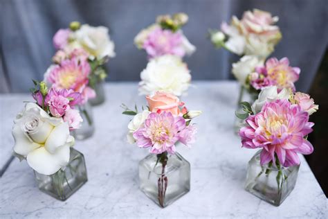 Mini bud vase arrangement in clear bottles featuring beautiful dahlias and roses. Pink and pale ...