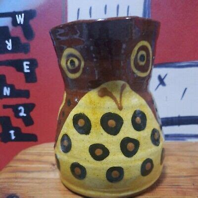 a ceramic owl vase sitting on top of a wooden table