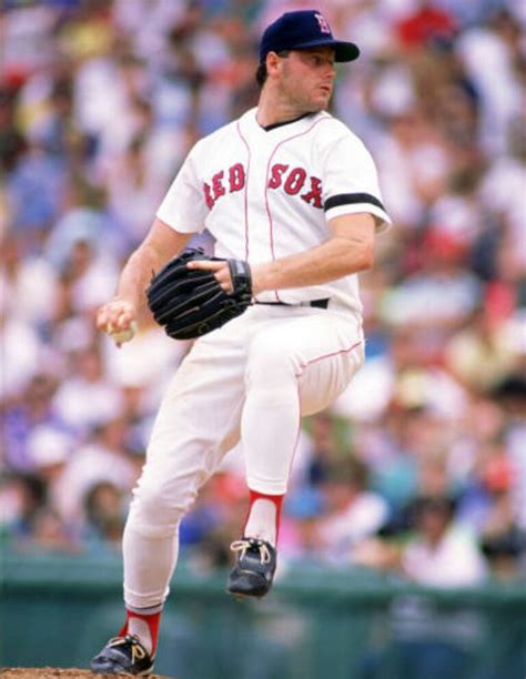 a baseball player pitching a ball on top of a field in front of a crowd