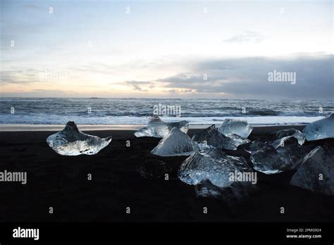 Broken ice cubes scattered on a sandy beach shoreline Stock Photo - Alamy