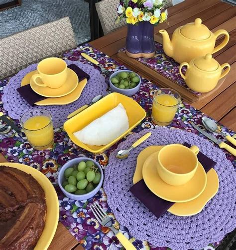 the table is set with yellow dishes and purple placemats