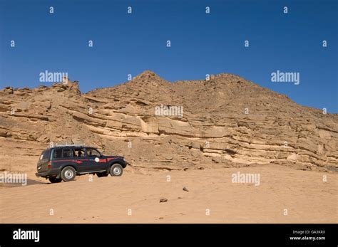 SUV climbing rock, Akakus, Acacus Mountains or Tadrart Acacus, Sahara desert, Fezzan, Libya ...