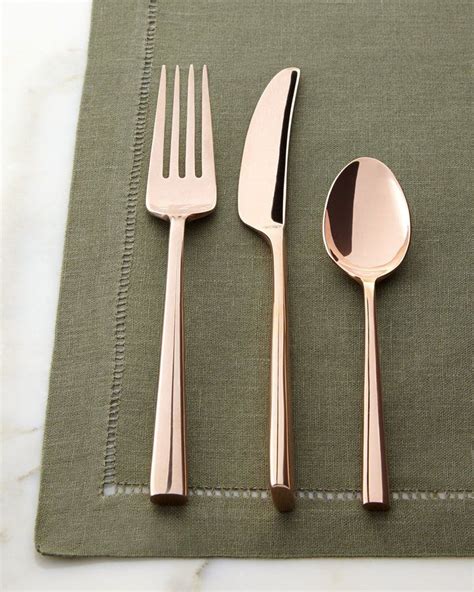 three forks, two spoons and one knife on a green place mat with stitched edges