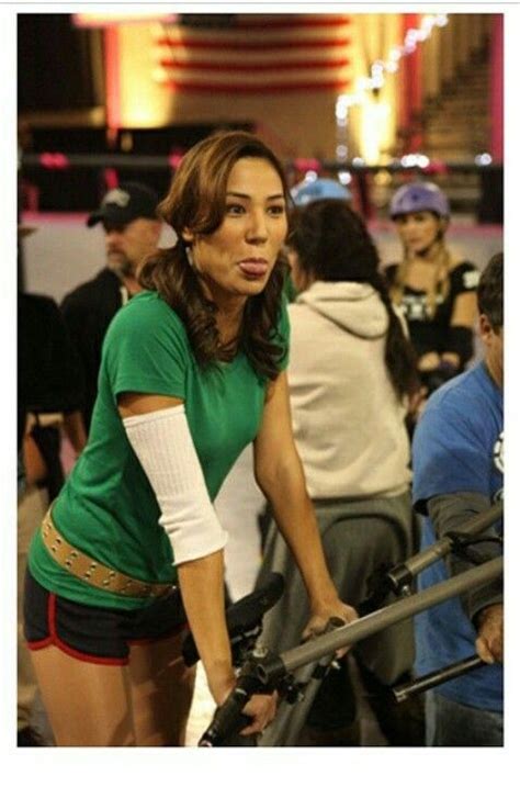 a woman in green shirt standing next to a bike with people around her and other people behind her