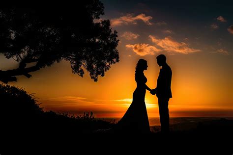 Silhouette of a newlywed couple on the background of the setting sun ...