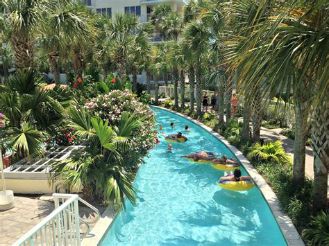 people are floating down the lazy waterslide at an outdoor swimming pool with palm trees