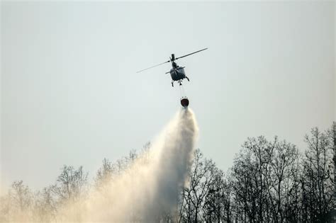 Premium Photo | Helicopter dropping water on forest fire