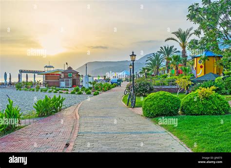 The seaside walk in Alanya with a view on Kleopatra beach and lush green gardens on sunset ...