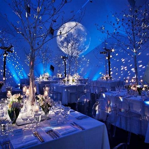 a table set up with white linens and silverware, lit by blue lights