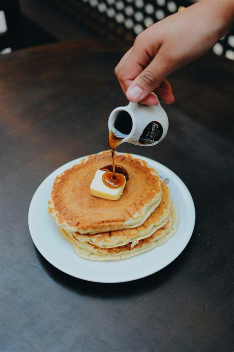 Photo of a Person Pouring Syrup on Pancake · Free Stock Photo