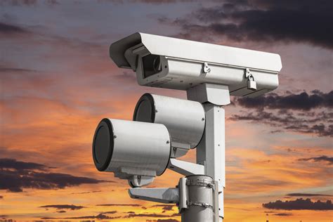 Traffic intersection signal surveillance camera with sunset sky. - Beninato & Matrafajlo