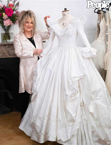 A Woman Standing Next To A Wedding Dress On A Mannequin In A Room