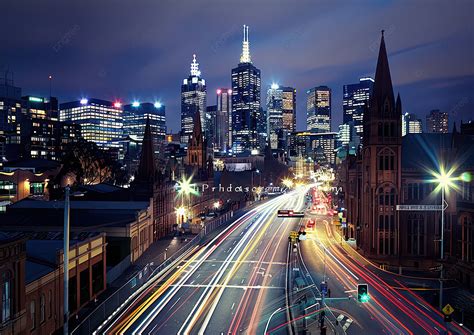 A Vibrant City Skyline At Night With Light Trails And Historic