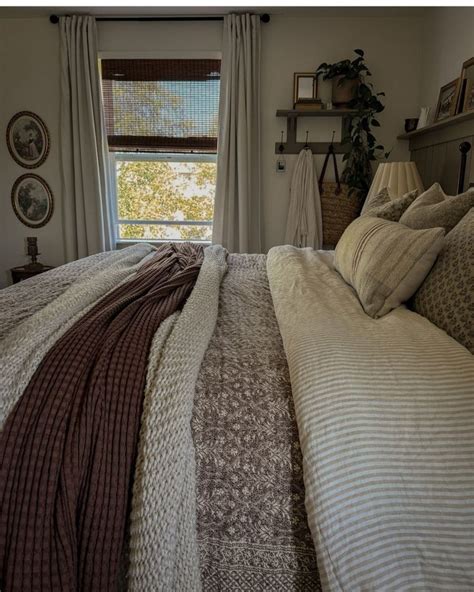 A Bed Sitting Under A Window In A Bedroom Next To A Lamp And Pictures