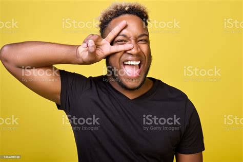 A Cheerfully Smiling Black Guy Shows A Symbol Of Peace Stock Photo