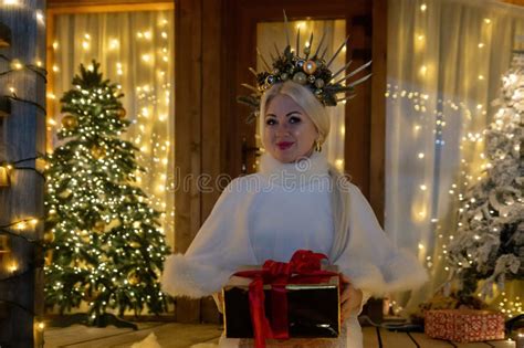 Happy Blonde As Snow Maiden In White Costume Wooden House Exterior Festive Setting Stock Photo