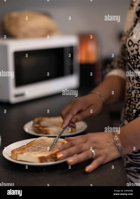 Woman Buttering Toast In Kitchen Stock Photo Alamy