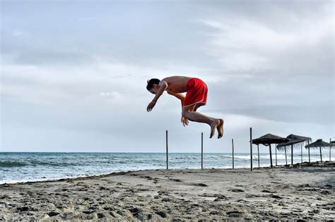 Premium Photo Young Man Doing Backflips Somersaults In The Sand