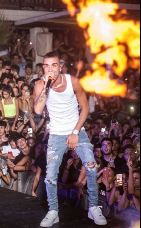 A Man Standing On Top Of A Stage Holding A Microphone In Front Of A Crowd