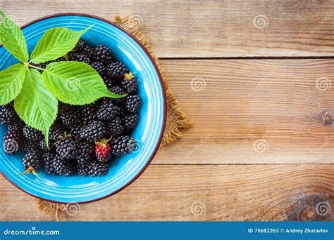 Fresh Blackberries With Leaves In Blue Ceramic Bowl On Wooden