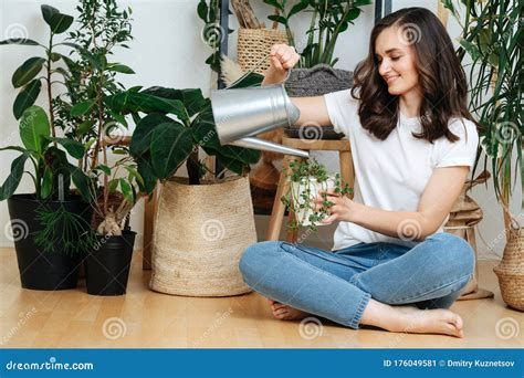 Una Mujer Vierte Agua En Una Maceta De Flores Imagen De Archivo