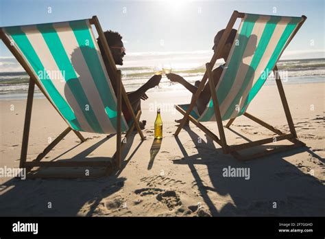 African American Couple In Love Sitting In Deckchairs Enjoying Drinks