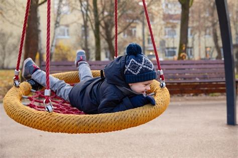 Un Ni O Sonriente Feliz Monta Un Columpio En Un Parque Infantil Hamaca